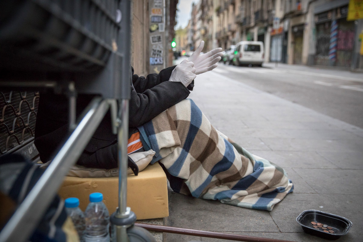 A man from Poland is putting a pair of gloves to protect himself from the virus although he has no mask. Since there is no people in the streets, he has problems to win money and pass the day. Raval quarter, city center of Barcelona. March 24. // Un hombre de Polonia se está poniendo guantes para protegerse del virus, aunque no tiene máscara. Como no hay gente en la calle, tiene problemas para conseguir dinero y pasar el día. Barrio del Raval, Barcelona. 24 de marzo. Foto: Eva Parey